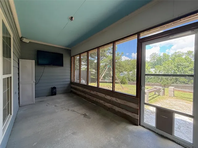 An inviting screened porch offers serene views of the green backyard, perfect for enjoying outdoor moments.