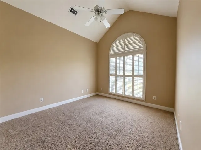 A vaulted ceiling crowns this inviting space, complemented by a large arched window with elegant shutters.