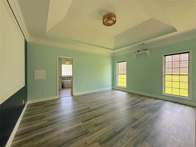 Recessed ceiling details enhance this airy room with durable wood flooring and ample natural illumination.