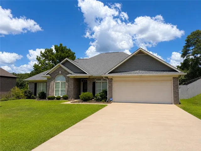 A classic brick exterior offers timeless curb appeal, complemented by a neatly manicured lawn and attached garage.
