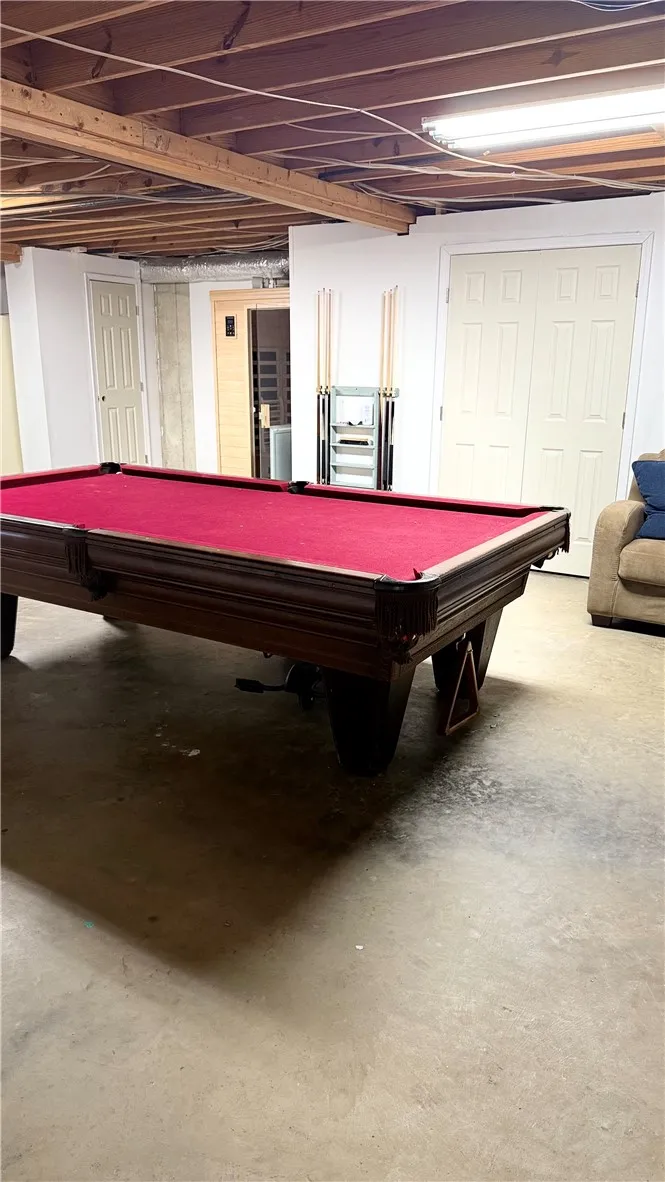 This spacious basement offers ample room for recreation and relaxation, featuring exposed ceiling joists.