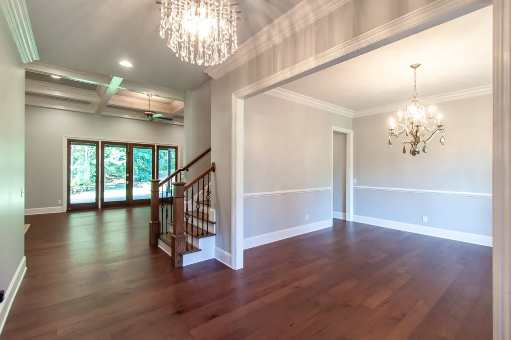 Grand foyer with dark wood flooring and a classic staircase flows into elegant living spaces.