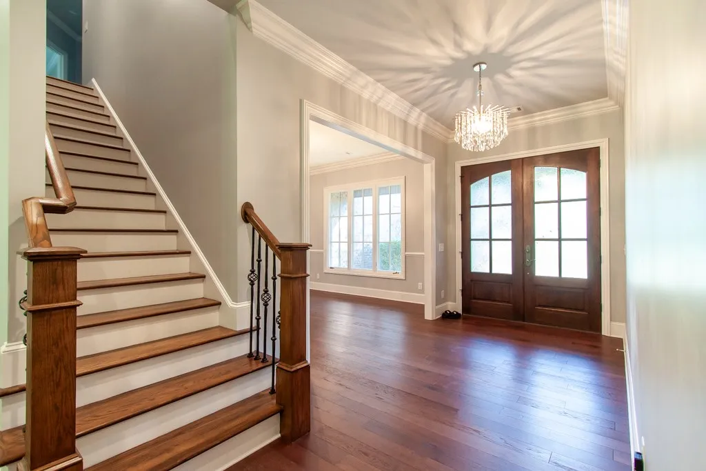 A grand entry with a sparkling chandelier and rich hardwood flooring sets a welcoming tone.