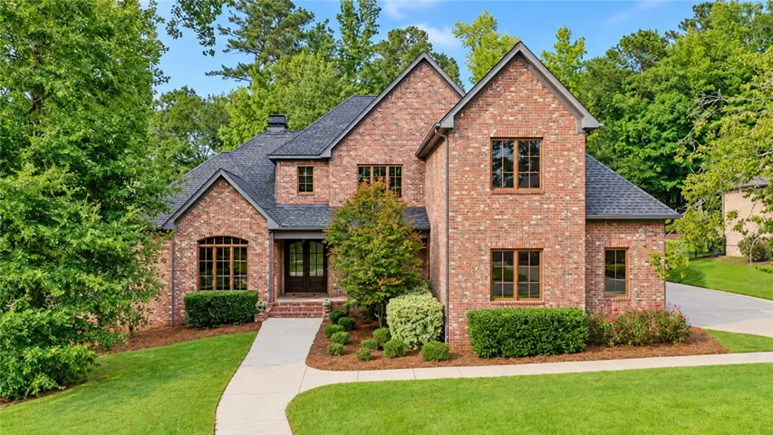 An elegant brick facade rises amidst lush green lawns and manicured perimeter plantings.