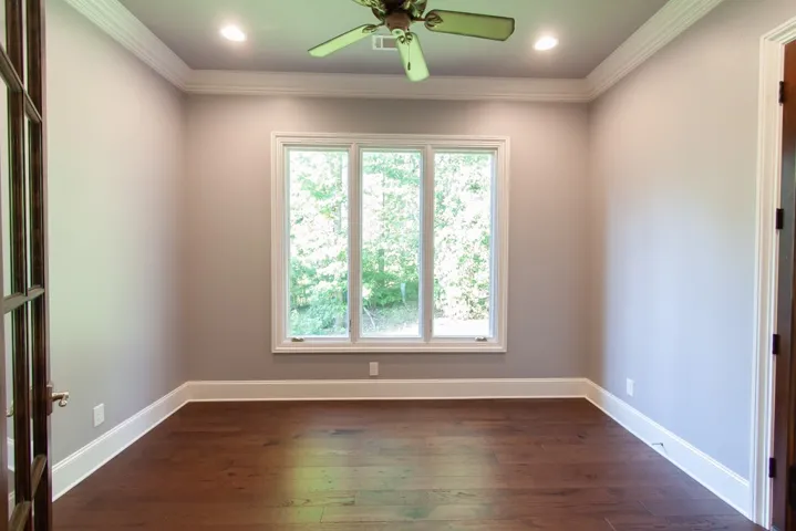 Off the primary bedroom, hardwood floors and generous crown molding define this versatile interior space, perfect for an office or study.