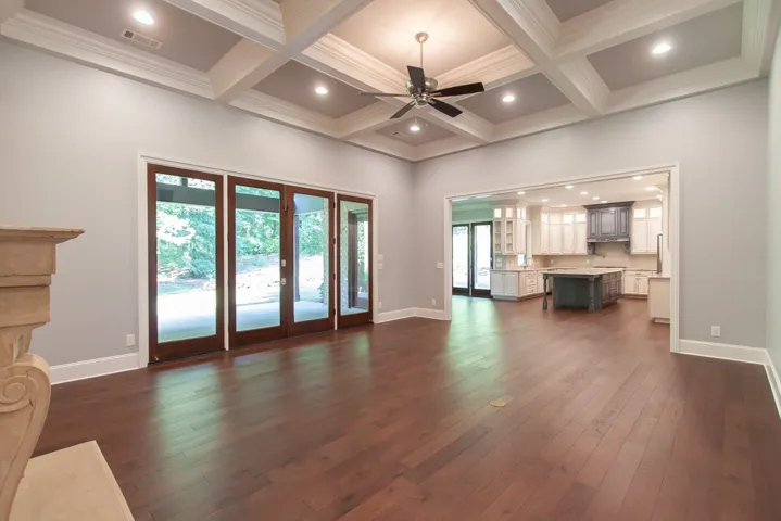 An open-concept living area flows seamlessly into a well-appointed kitchen, all under a beautifully coffered ceiling.