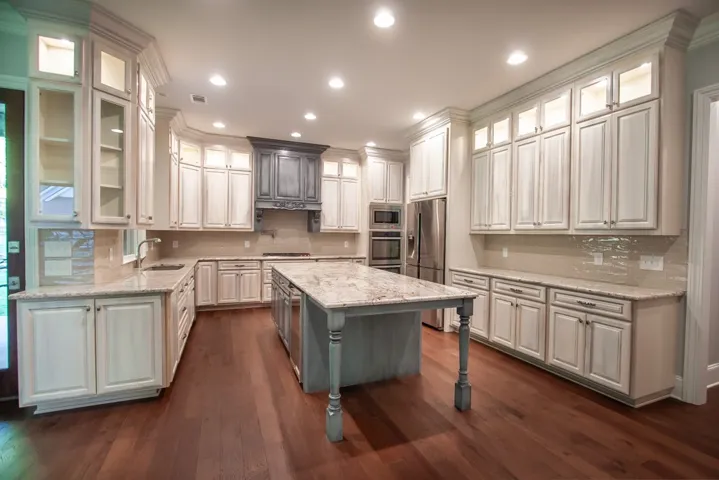 An inviting kitchen with rich hardwood floors, an elegant stone island, and extensive cabinetry for culinary pursuits.