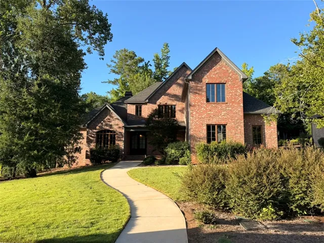 A graceful curved walkway guides visitors to the inviting entryway of this stately brick residence.