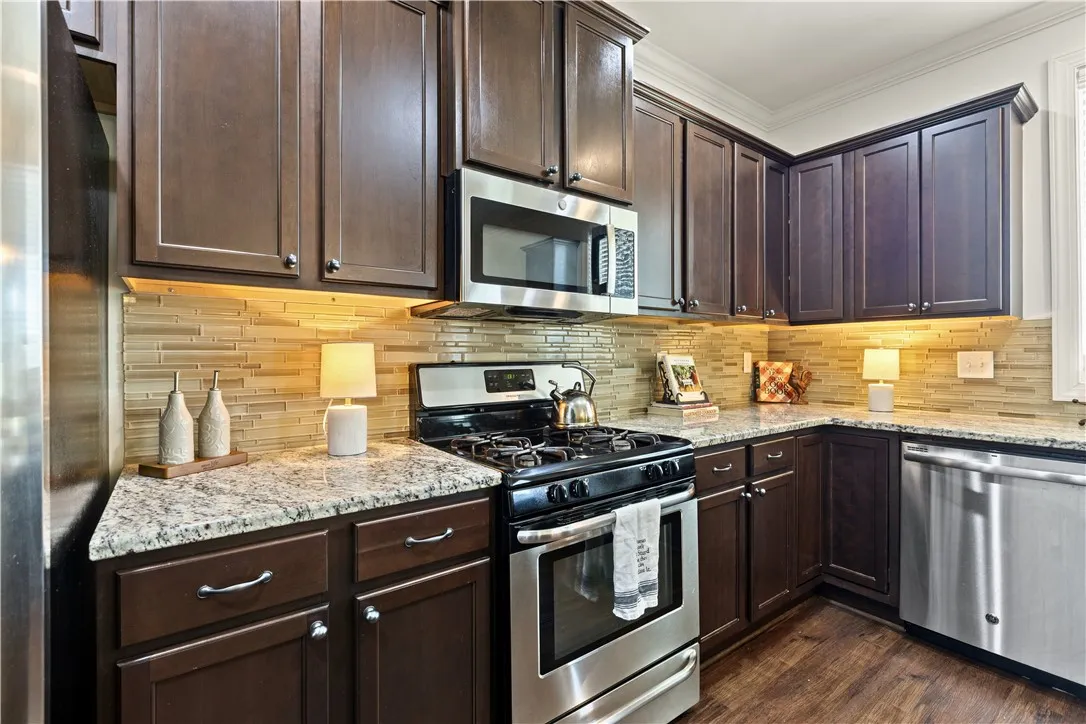 Beautiful kitchen with granite countertops, rich cabinetry, gas stove, new microwave, and dishwasher