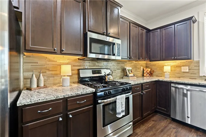 Beautiful kitchen with granite countertops, rich cabinetry, gas stove, new microwave, and dishwasher
