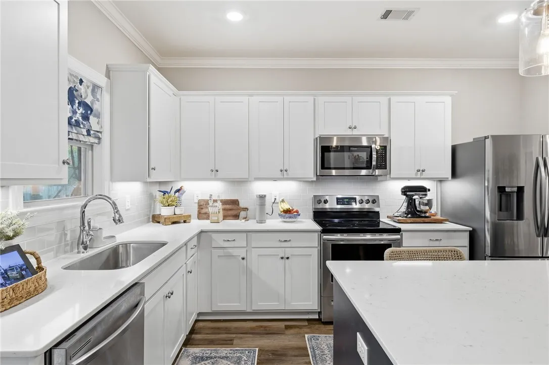 White cabinetry, solid surface counters, and stainless steel appliances complete this bright, contemporary kitchen.