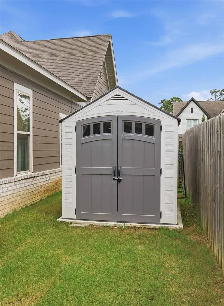 A well-maintained backyard shed provides convenient outdoor storage alongside the home's brick foundation and fenced perimeter.