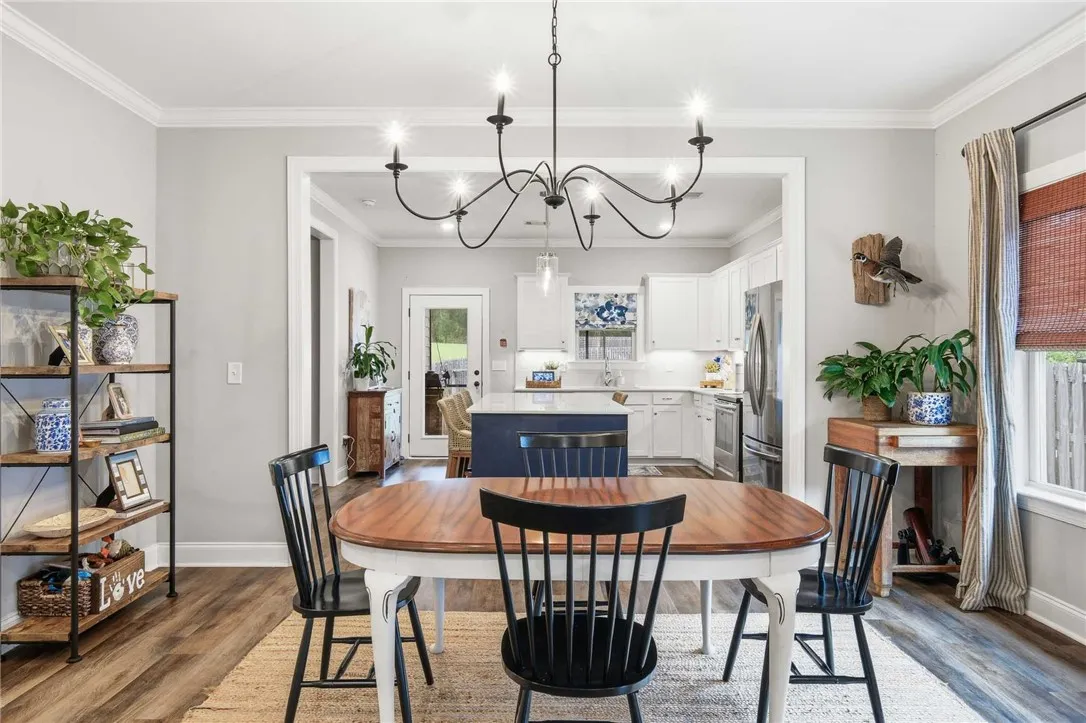 An inviting open-concept layout connects the dining area, featuring a modern chandelier, to a well-appointed kitchen beyond.
