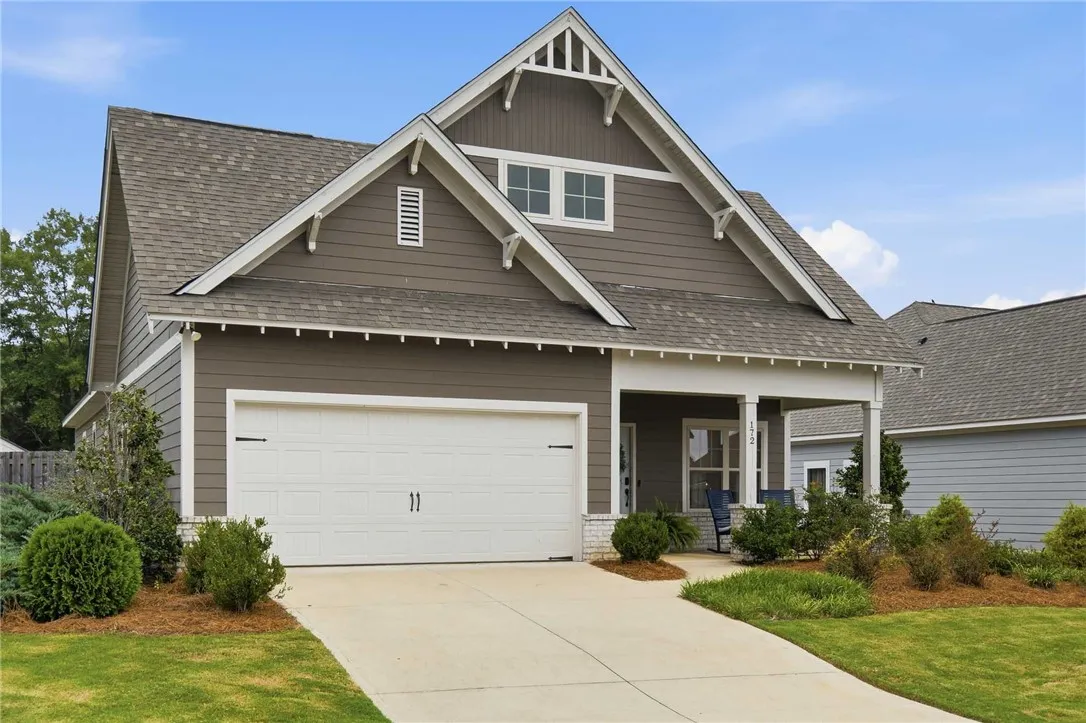 Craftsman-style home with a welcoming front porch, a spacious driveway, and lush, manicured landscaping.