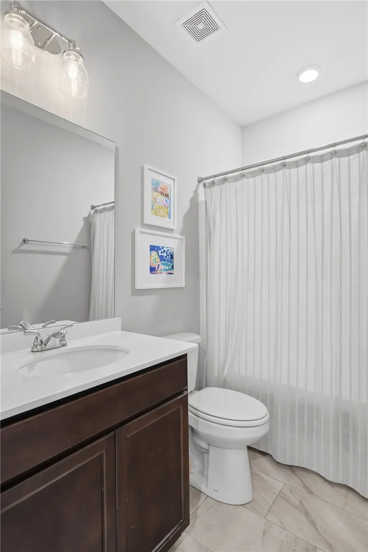 A well-appointed bathroom features a dark wood vanity, modern fixtures, and a clean shower area.