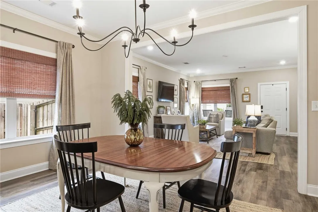An inviting open-concept layout connects the dining area with a comfortable living space, featuring rich wood flooring and crown molding.