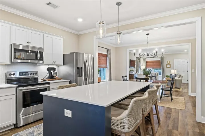 A well-appointed kitchen features a large island and stainless steel appliances, opening to an inviting living area.
