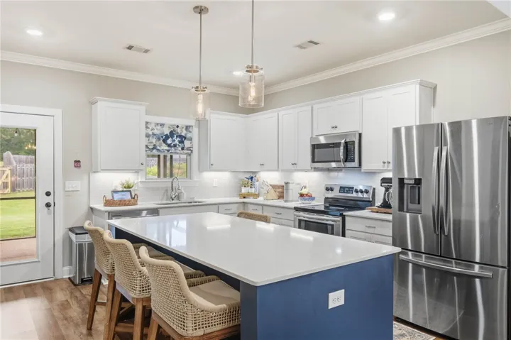 Culinary adventures await in this kitchen, featuring an oversized island, stainless appliances, and crisp white cabinetry.