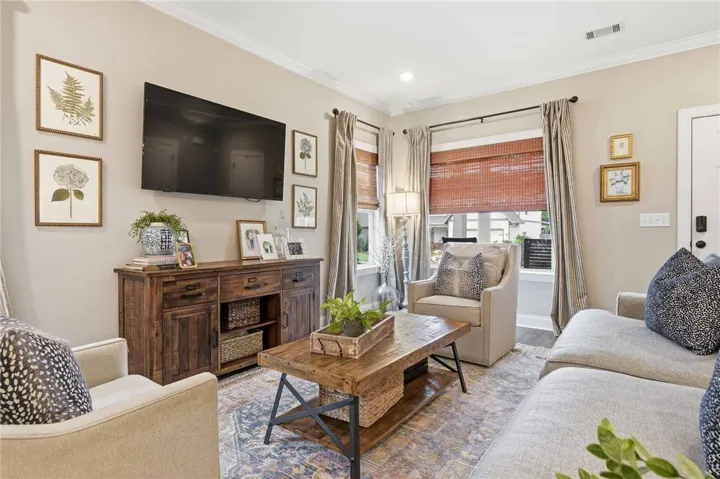 A welcoming living area showcases crown molding and a patterned area rug, perfect for comfortable gatherings.