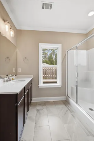 A bright bathroom with a spacious vanity, tiled floor, and walk-in shower.