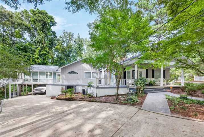 A spacious elevated residence with expansive decking and a charming covered front porch, perfect for outdoor living.