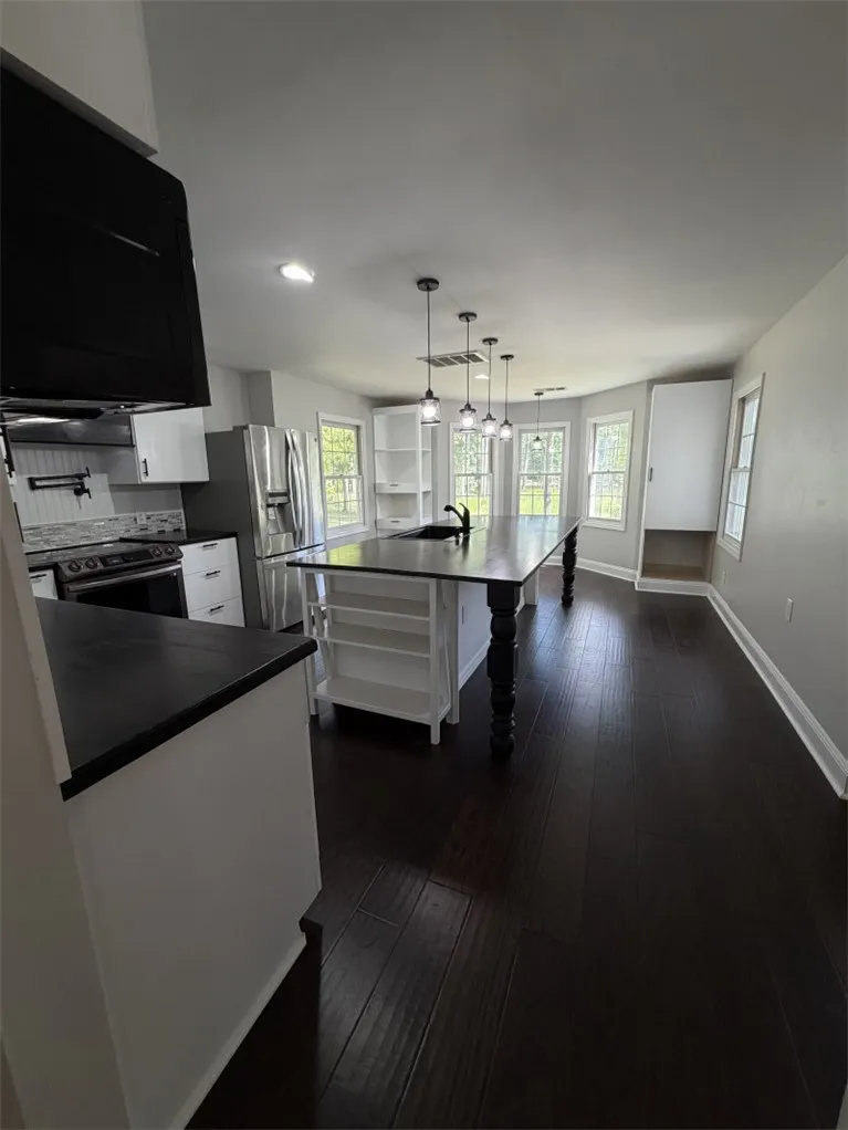 An inviting kitchen with a substantial island and gleaming dark hardwood floors awaits culinary adventures.
