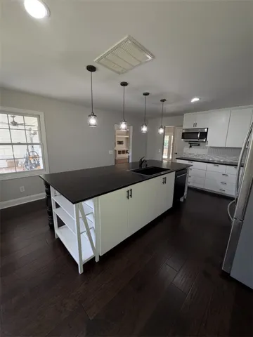 A well-appointed kitchen showcasing a spacious central island, sleek dark countertops, and rich hardwood flooring.
