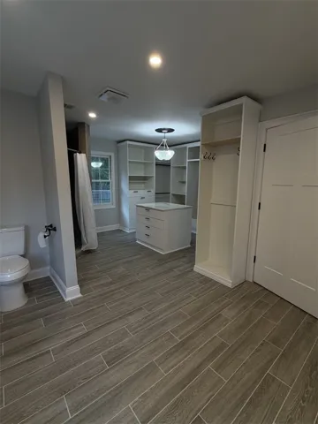 A well-appointed primary bathroom features a spacious walk-in closet with built-in storage solutions and elegant tile flooring.