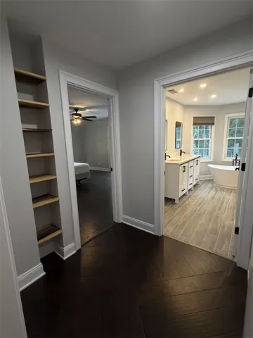 Rich hardwood floors welcome you to a spacious, well-appointed bathroom featuring dual vanities and a freestanding tub.