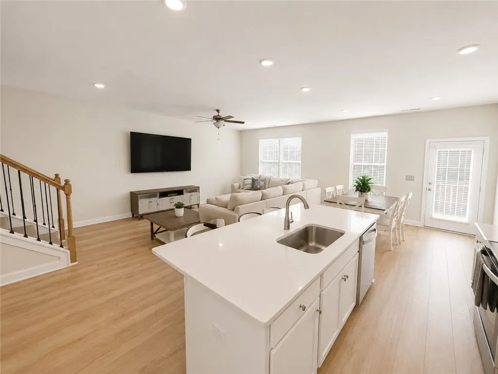 An open-concept living space with sleek hardwood flooring and recessed lighting offers comfortable gathering.