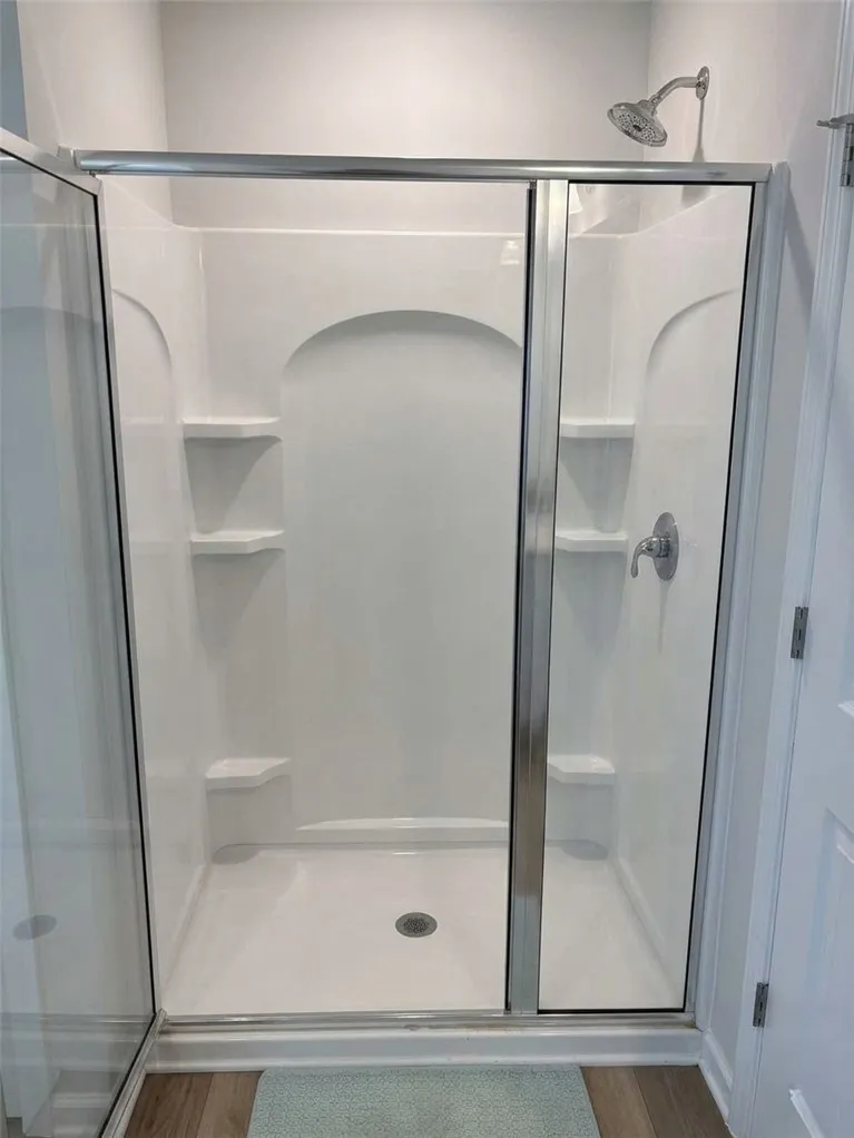 Step into this contemporary walk-in shower, featuring sleek glass doors and built-in shelving.