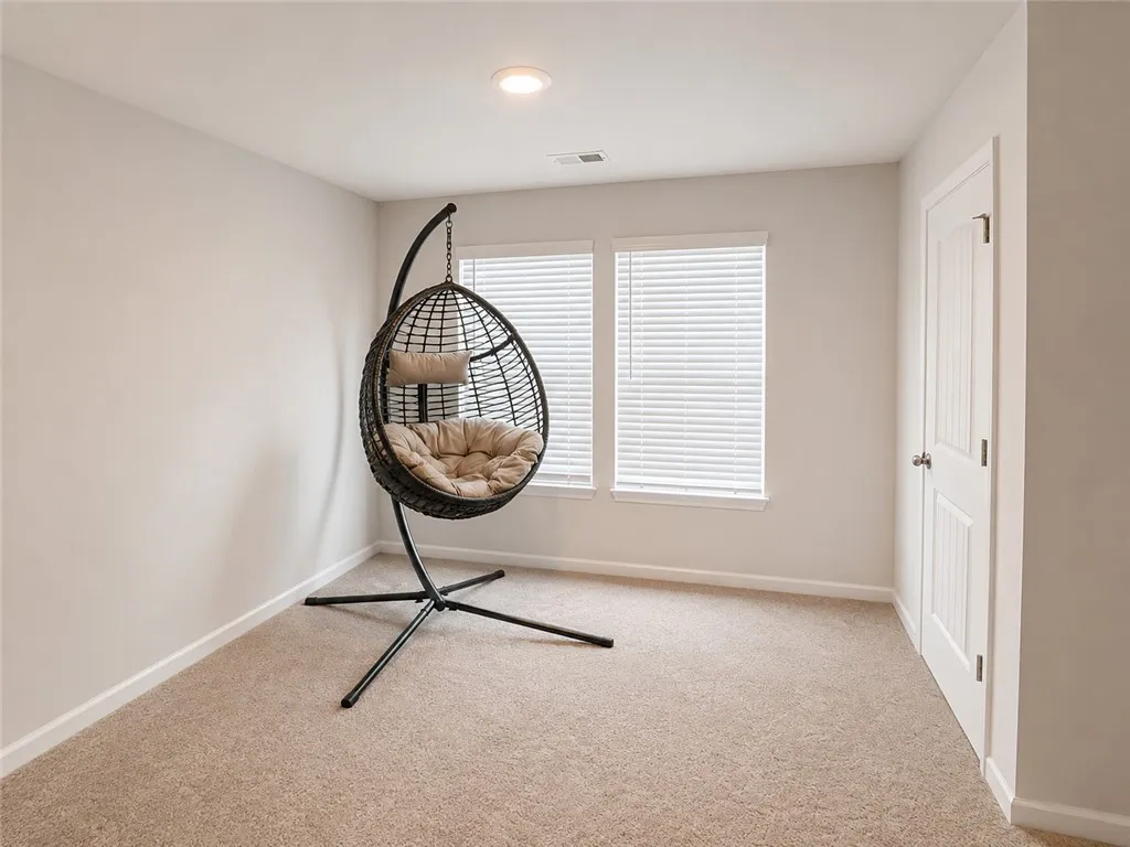A comfortable bonus room with plush carpeting and natural light from broad windows.