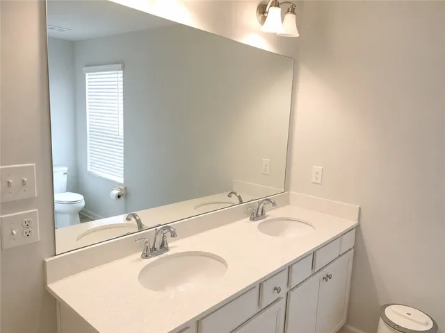 Double vanities with sleek countertops provide ample space in this well-appointed bathroom.