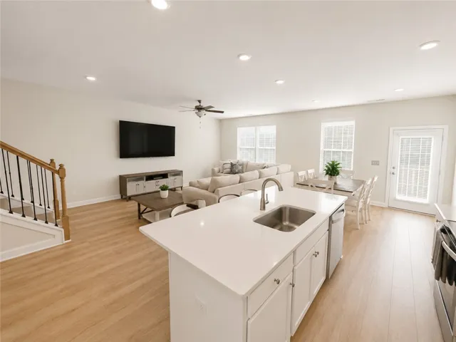 An open-concept living space with sleek hardwood flooring and recessed lighting offers comfortable gathering.