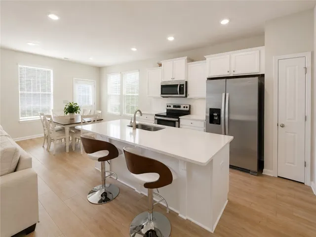 A well-lit kitchen with sleek stainless steel appliances, a generous island, and an inviting dining area.