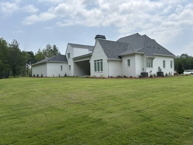 A pristine, well-maintained lawn embraces this elegant white brick home with its multi-gabled roofline.