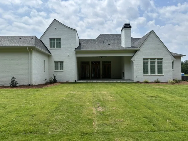 A well-kept lawn complements the bright brick facade and inviting covered patio.