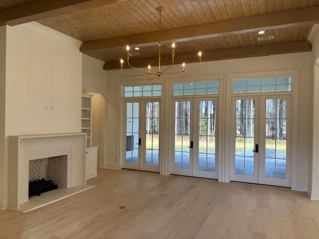 Beamed wood ceilings and a classic fireplace anchor this open living area facing the terrace.