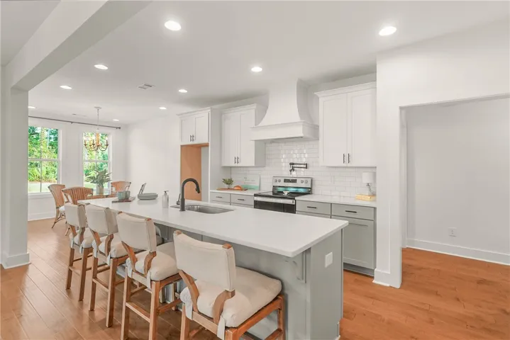 Kitchen features a large center island, farm sink, quartz countertops and wood hood