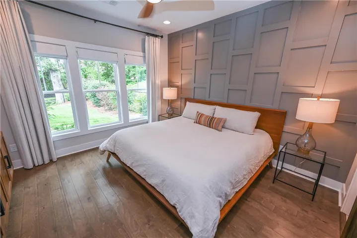 Elegant primary bedroom includes a custom accent wall and oversized windows overlooking the backyard