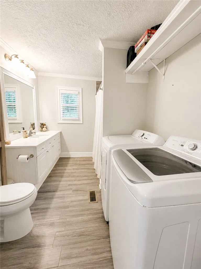 A well-appointed utility area featuring modern laundry appliances and a functional bathroom vanity.