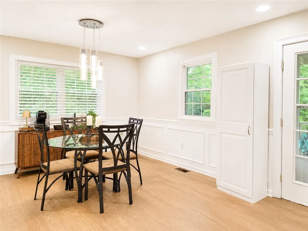 Hardwood-style flooring extends across this bright dining space, featuring classic wainscoting and natural light from multiple windows.