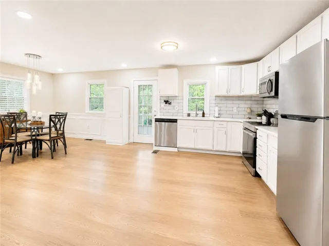 An open concept kitchen and dining space with light wood flooring and contemporary finishes awaits.