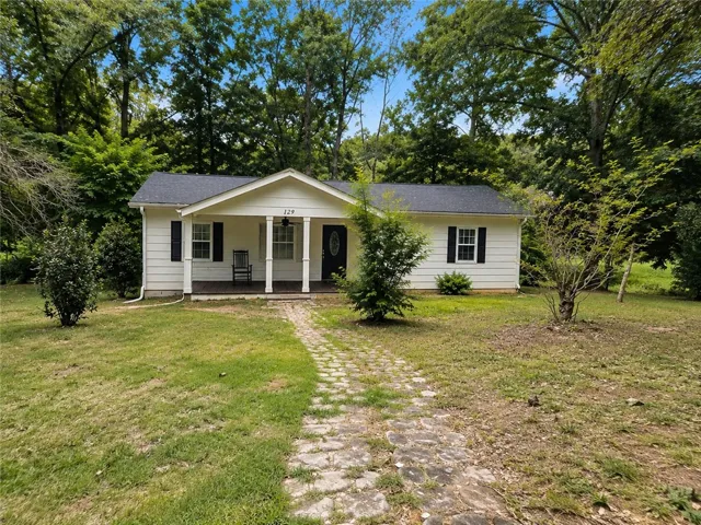 A charming single-story residence with a welcoming front porch and a winding stone pathway.