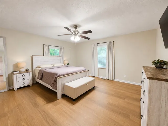 Well-lit sleeping quarters with rich wood-look flooring and a functional ceiling fan for optimal comfort.