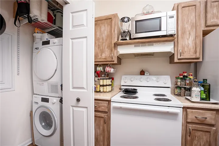 Functional kitchen with ample cabinet space, a range, and convenient in-unit laundry.