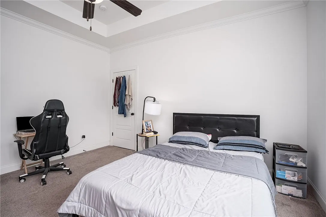 Primary bedroom features carpeted flooring and tray ceiling.