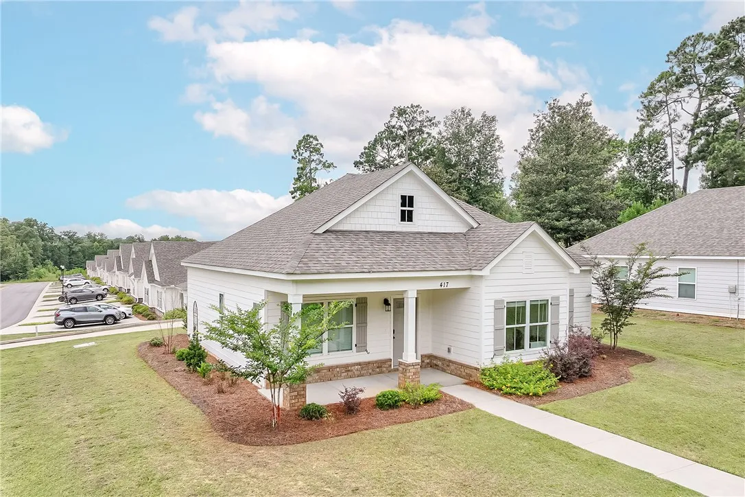 Welcoming covered porch, a well-kept lawn, with surrounding natural foliage.
