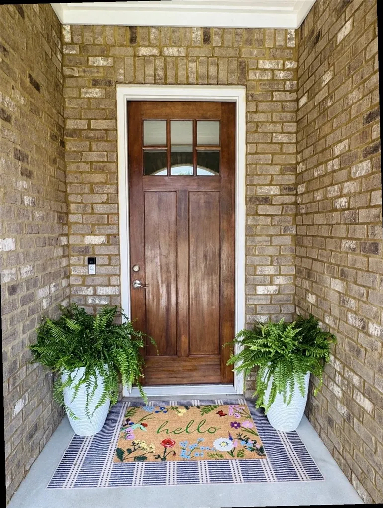 A welcoming front entry features a rich wooden door framed by classic brick.