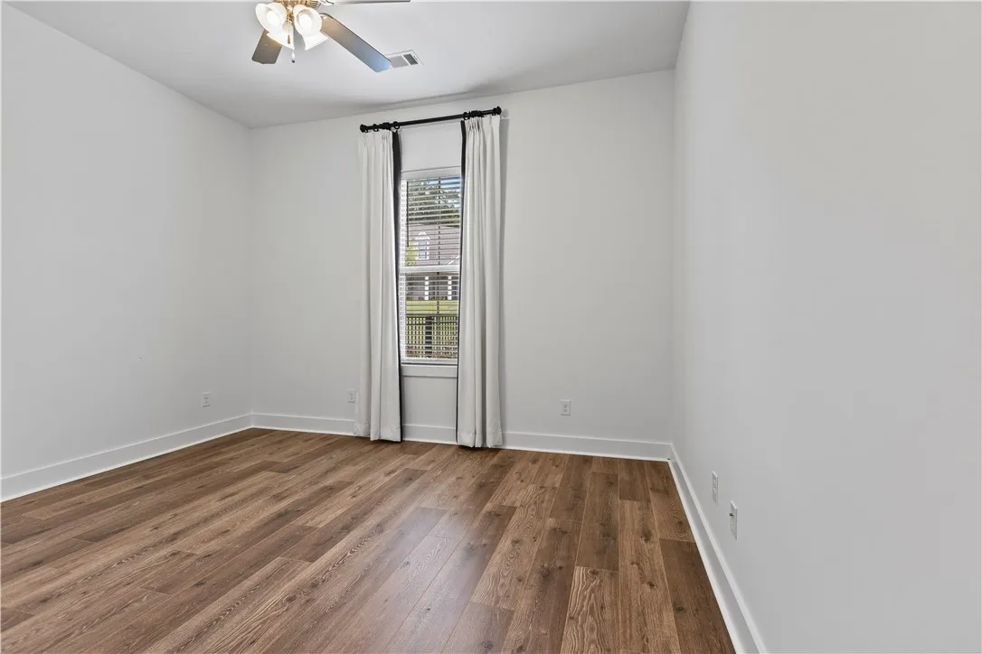 Bedroom 3 on the left side of the home with custom drapes that can convey with the home or be removed (ensuite)